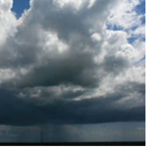 A picture of a large thundercloud and rain falling in a field