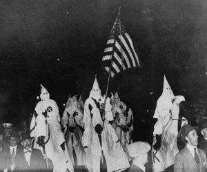 Photo of KKK members waving an American flag from the 1920s