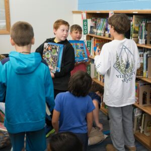 A group of boys share books they found in the shelves.