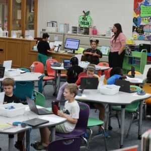 A busy library showing students engaged in checkout and desk work.