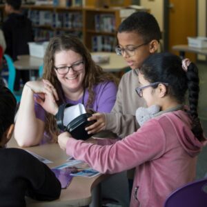 The librarian smiles as she helps students with an activity.