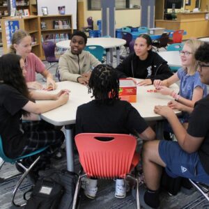 Hope squad meets in the library and plays games around a table.