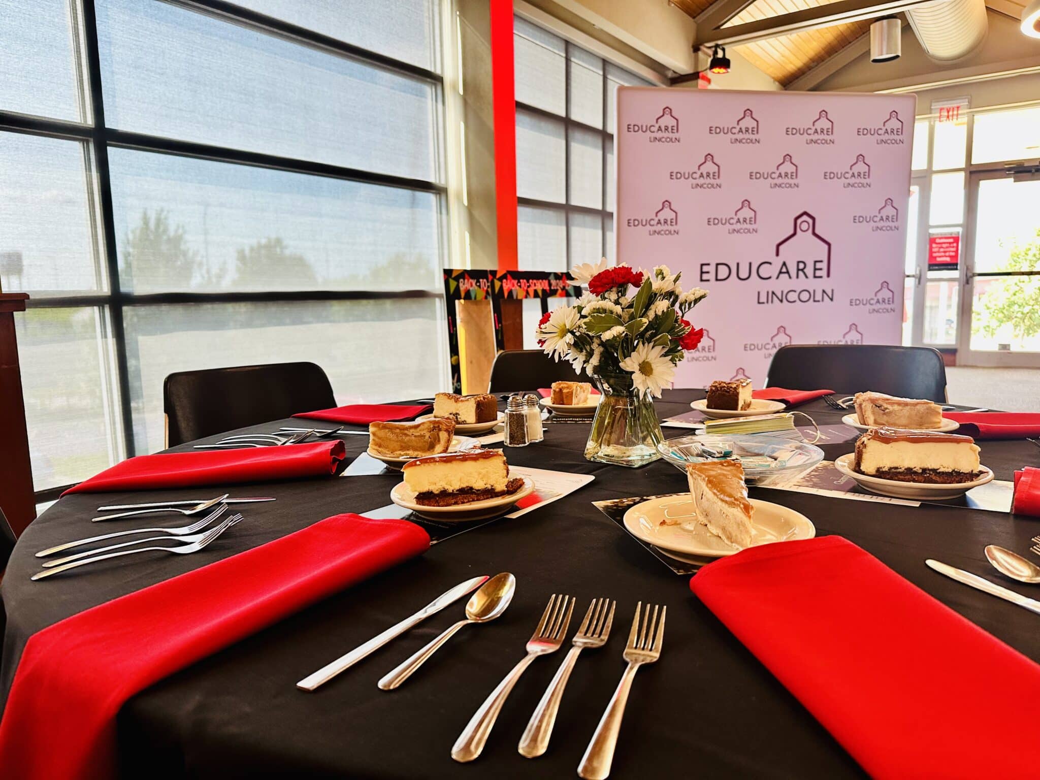 A dining table set with napkins, silverware and deserts.