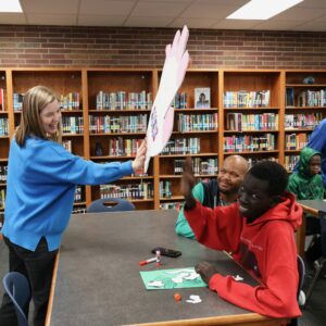 An oversized high five hand is held by the librarian for students to use.