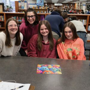 Four girls next to their completed puzzle in a competition.