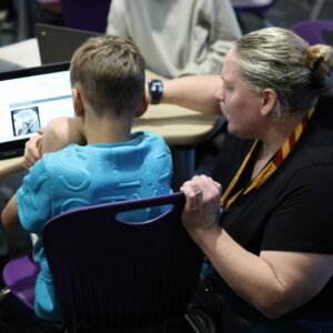 Mrs. Anderson helps a student find a book on the computer.