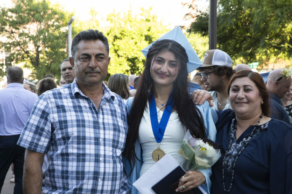 A father and mother standing with their daughter after the Standing Bear Graduation.