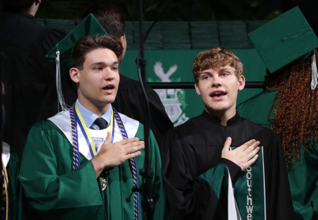 Students singing with their hands over their hearts
