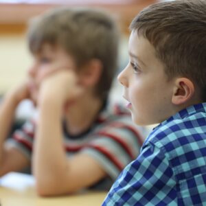 Two kids sit at a table listening to a read aloud book