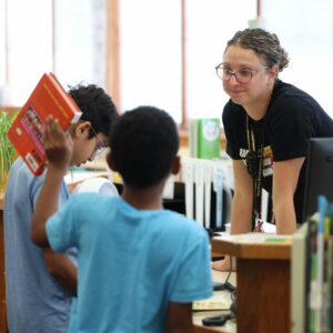 Mrs. Neff smiles at a boy who is showing off the book he checked out.