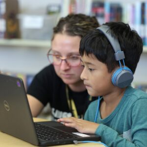 Mrs. Neff helping a student with their Chromebook