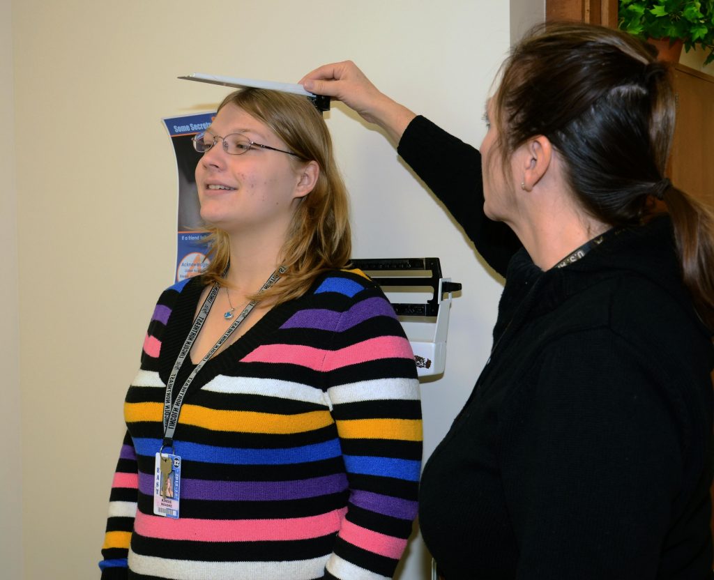 Photo of a student being screened for height and weight at a High School