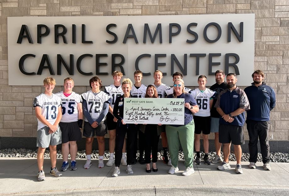 Members of Standing Bear's football team smile in front of the new April Sampson Cancer Center. The team raised $850 for cancer patients.