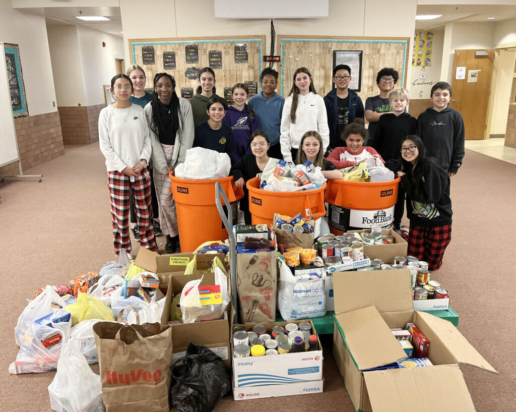 Scott Middle School students smile with hundreds of items they are donating to the Food Bank of Lincoln. Dozens of sixth grade A team (6A) students took part in a weeklong food drive.