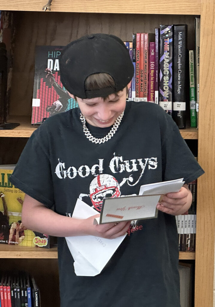 A Goodrich Middle School sixth grader smiles as he reads a thank you note from a North Gate Garden Estates resident.