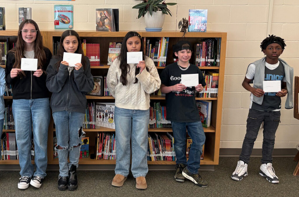 Goodrich Middle School sixth graders smile while holding thank you notes from North Gate Garden Estates residents.