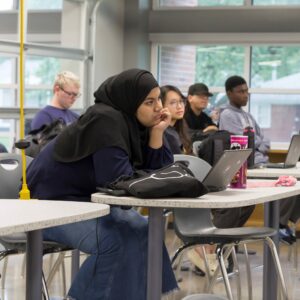 A group of students waiting for for instruction in the library.