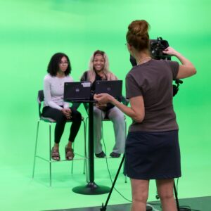Mrs. Broeker helps students in the green screen production room.