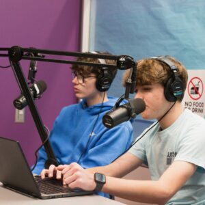 Two students using podcast equipment for a class.