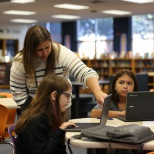 Mrs. Fickes helps a student on their computer.