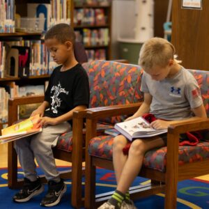 Two students read on comfortable chairs in the library.