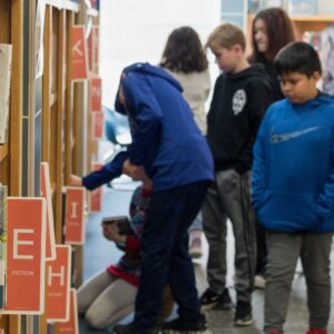 A group of students look for books in the shelves of the library.