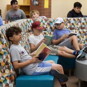 A group of students sits on comfortable furniture reading.