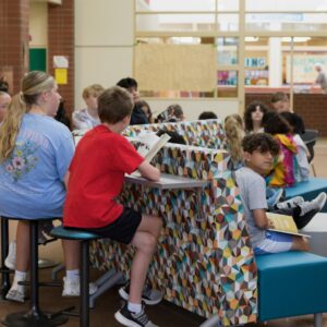 Students lounge in the library looking at their books and chatting.