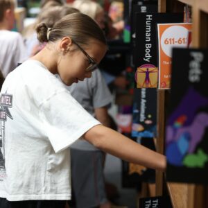 A student looks for a book on a shelf.