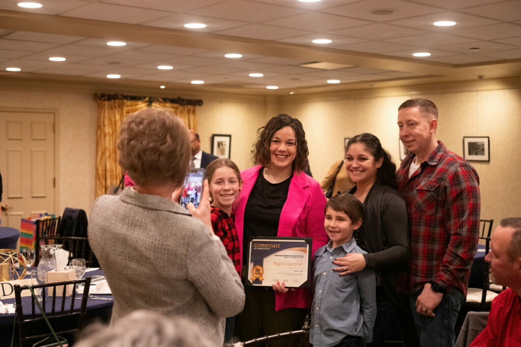 A teacher, a student and the student's family pose for a picture