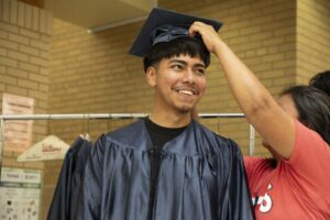 A student smiles as he is fitted with a cap and gown at Lincoln High School.