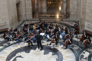 A photo of the Schoo Middle School orchestra performing on the floor of the Nebraska State Capitol
