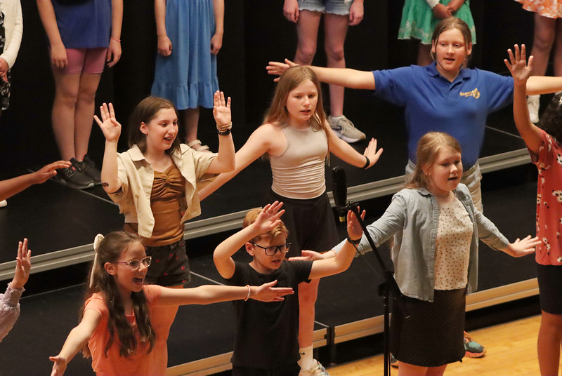 Singing students on risers with hands outstretched