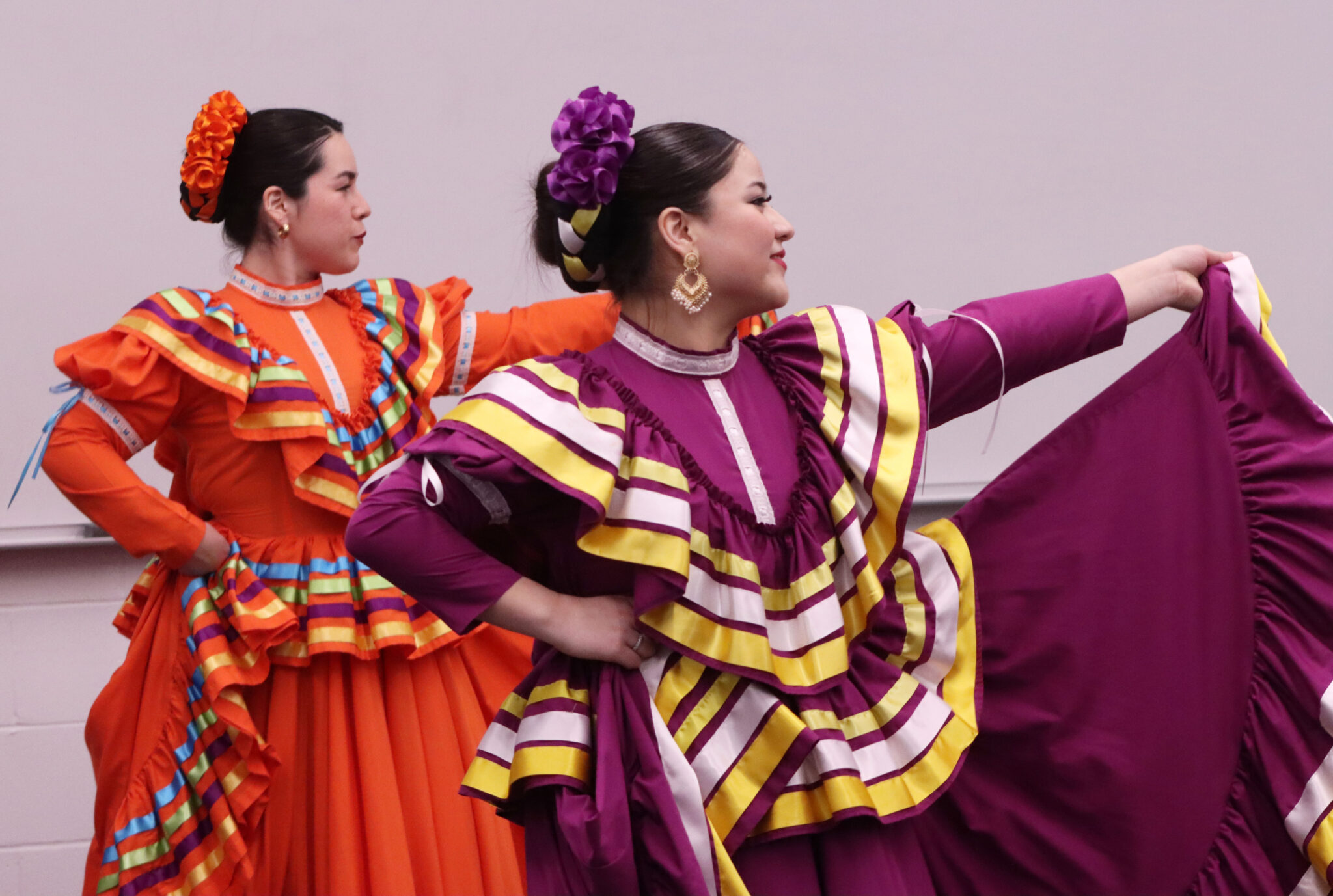 Two women perform a traditional dance for the audience at the 2026 LPS Hispanic Latino Senior Celebration. Both are using their left hands to wave their dresses.